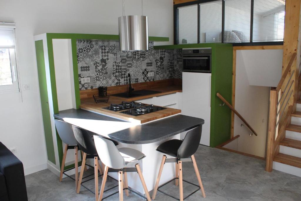 a kitchen with green walls and a table and chairs at ATELIER 85 in Les Épesses