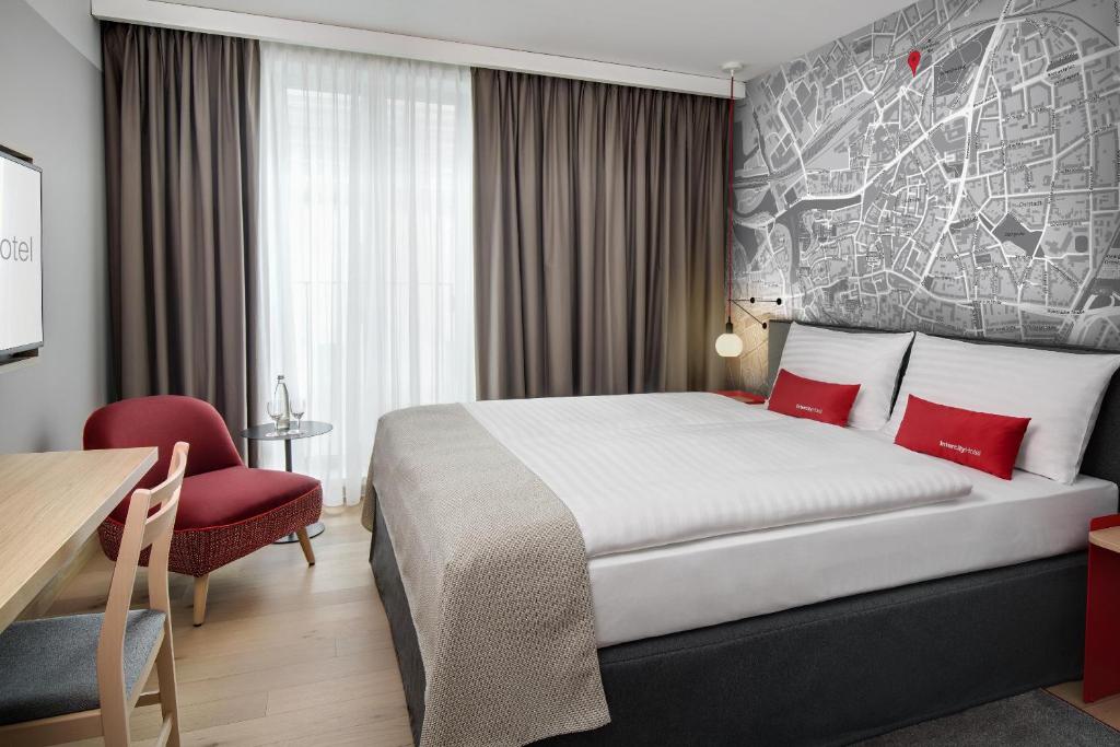 Habitación de hotel con cama y silla roja en IntercityHotel Hildesheim en Hildesheim