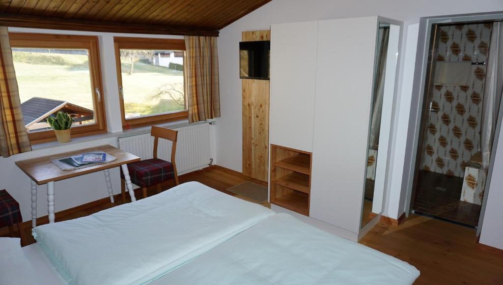 Schlafzimmer mit einem Bett, einem Tisch und einem Fenster in der Unterkunft Gästehaus Hubertus in Malta