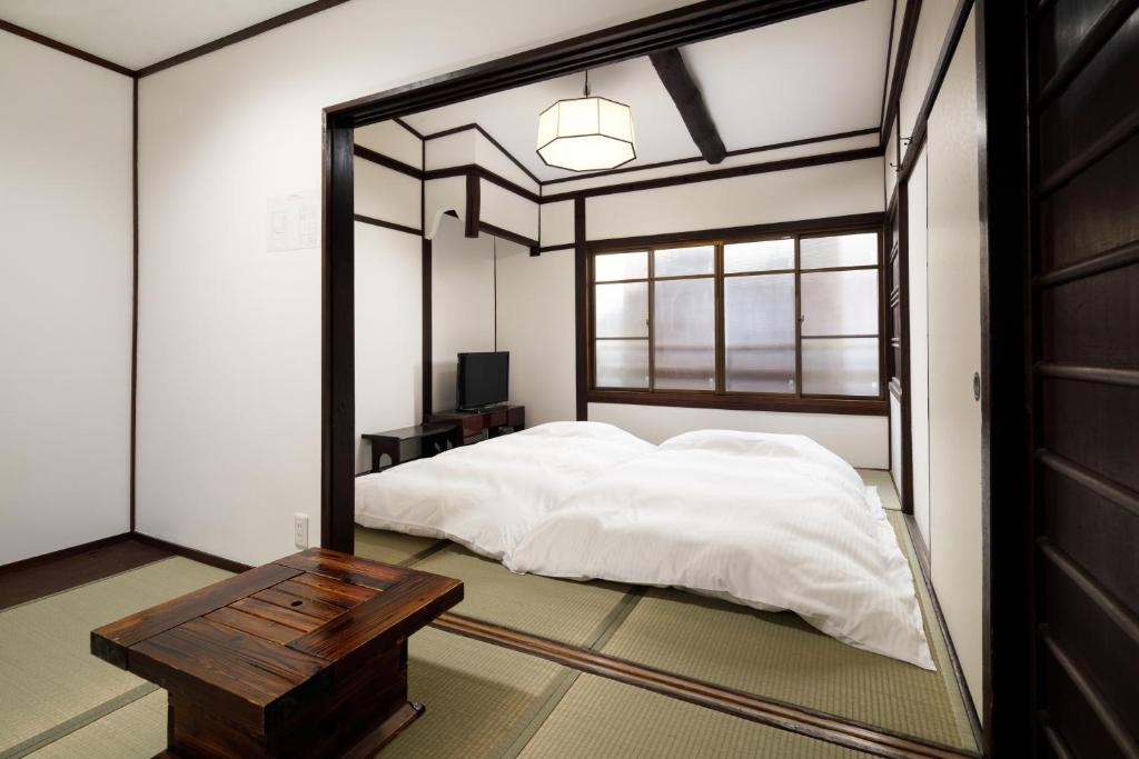 - une chambre avec un lit, une table et un miroir dans l'établissement Tsumugi Shichijo-Kagiyacho, à Kyoto