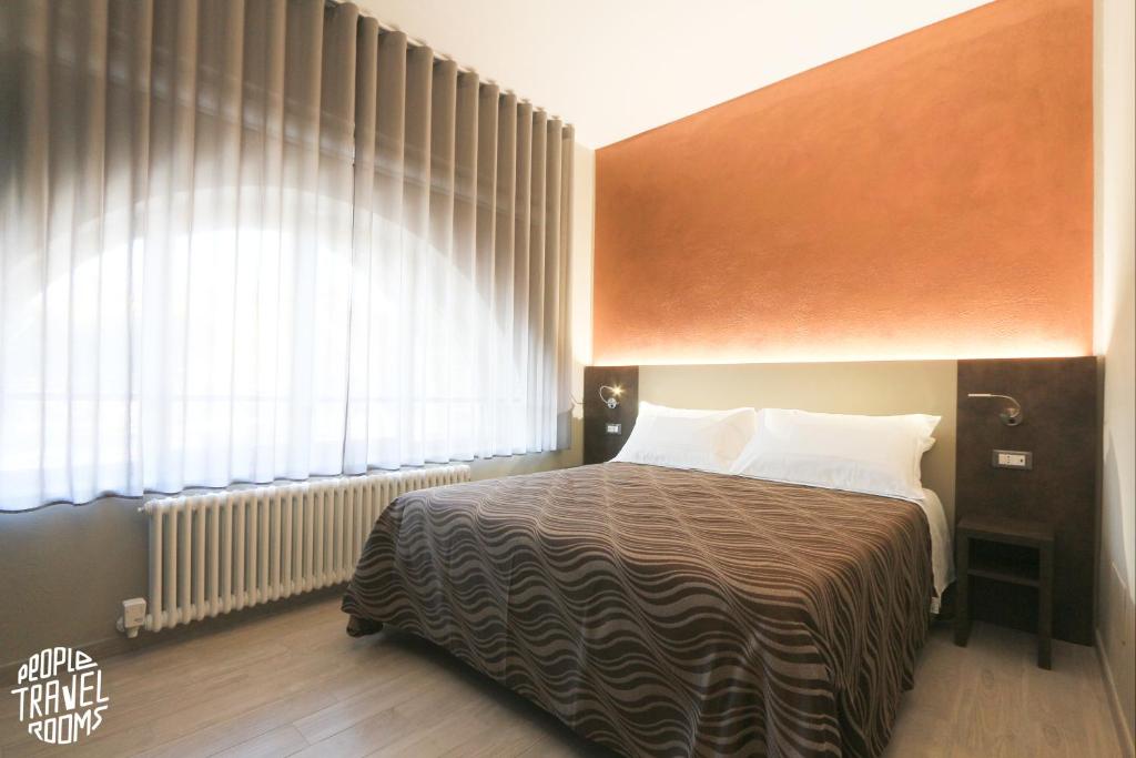 Schlafzimmer mit einem Bett und einem großen Fenster in der Unterkunft People Travel Rooms in Bologna