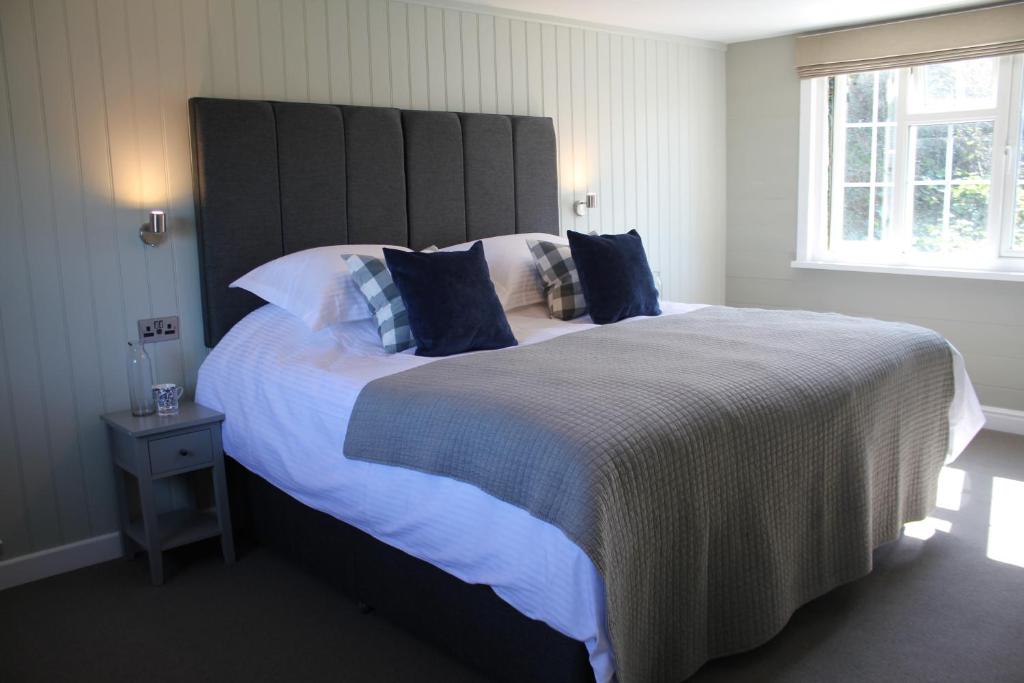 a bedroom with a large bed with blue pillows at The Five Pilchards Inn in Helston