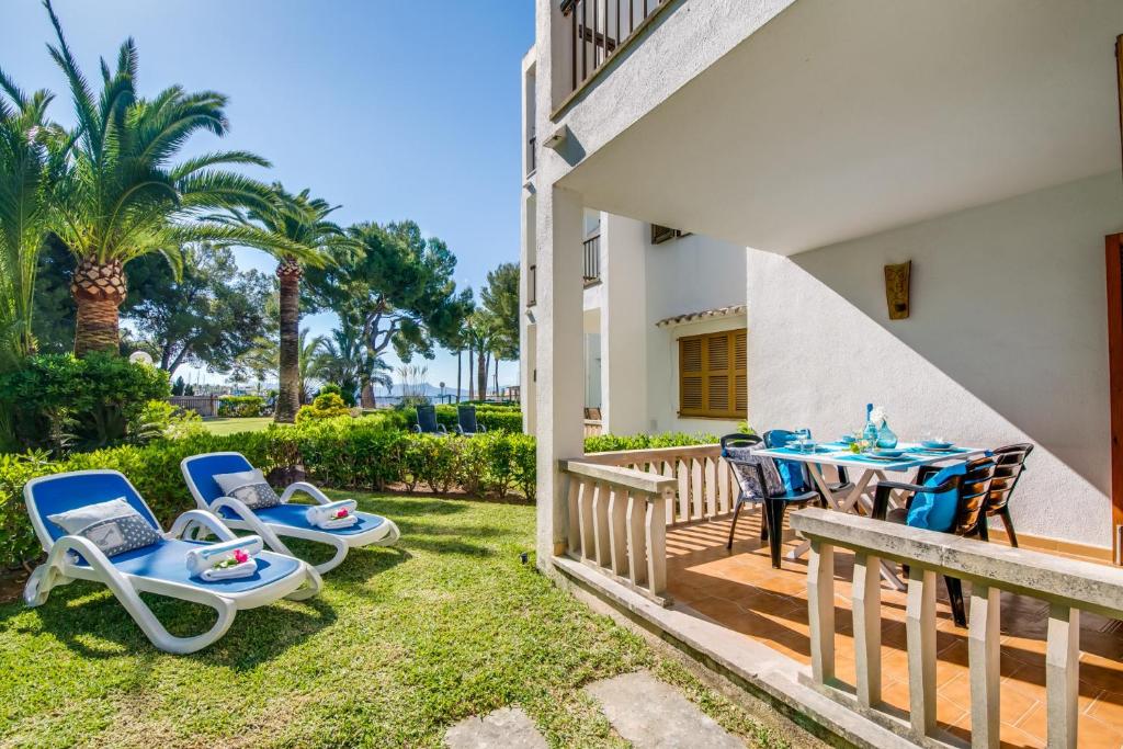 a patio with a table and chairs and palm trees at Ideal Property Mallorca - Playasol in Port d'Alcudia