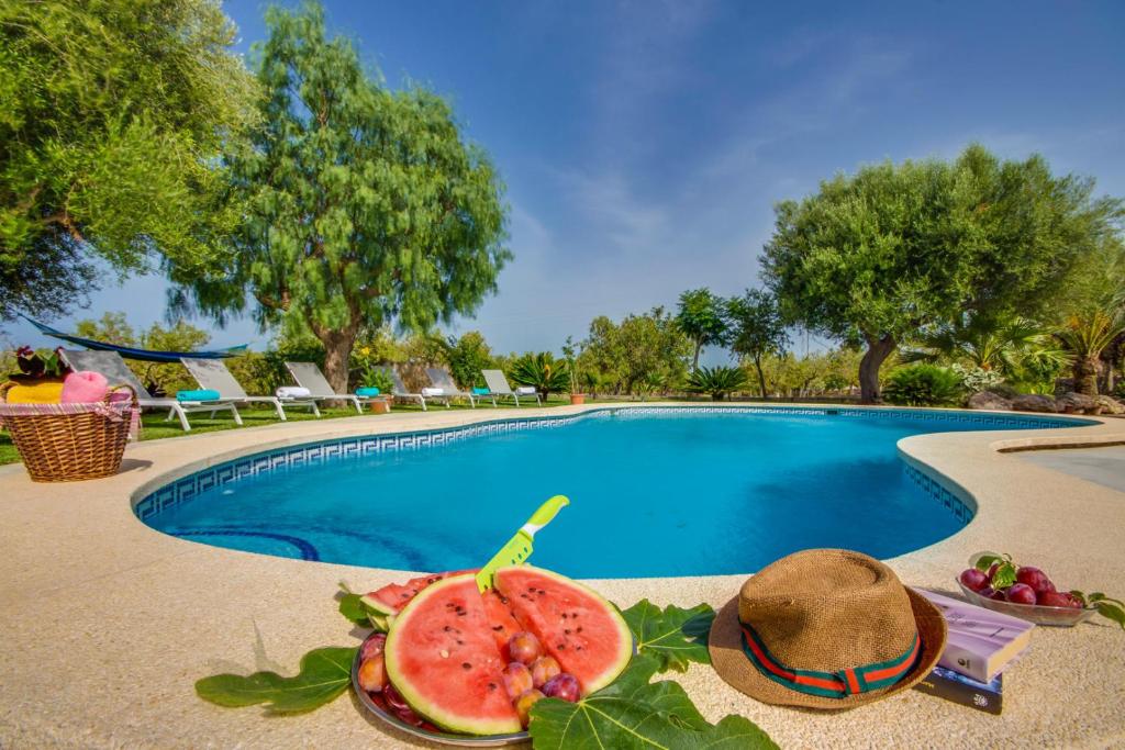 a bowl of watermelon and a hat next to a swimming pool at Ideal Property Mallorca - Vernissa in Santa Margalida