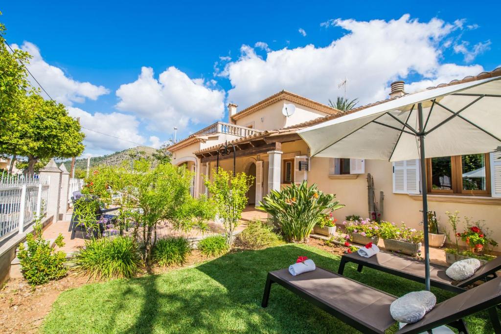 um pátio com um guarda-sol e cadeiras num quintal em Ideal Property Mallorca - Villa Celia em Port d'Alcudia