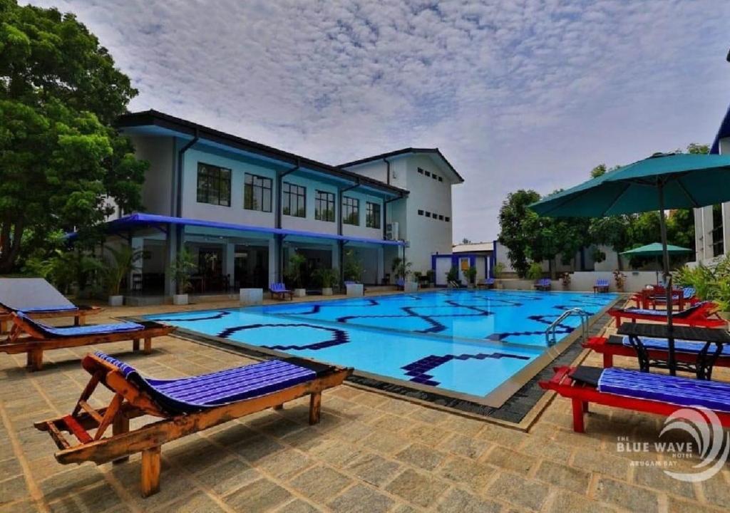 阿魯岡灣的住宿－The Blue Wave Hotel，一个带椅子和遮阳伞的大型游泳池