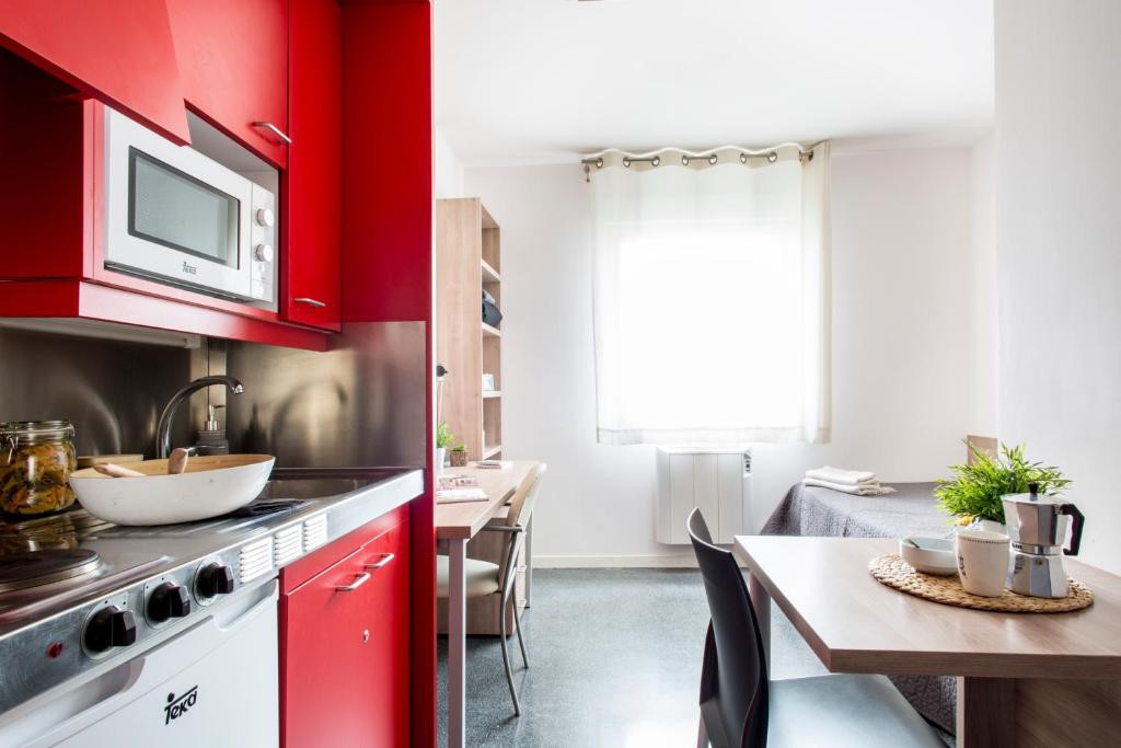 uma cozinha com armários vermelhos e uma mesa de jantar em Alojamientos Universitarios Hipatia em Terrassa