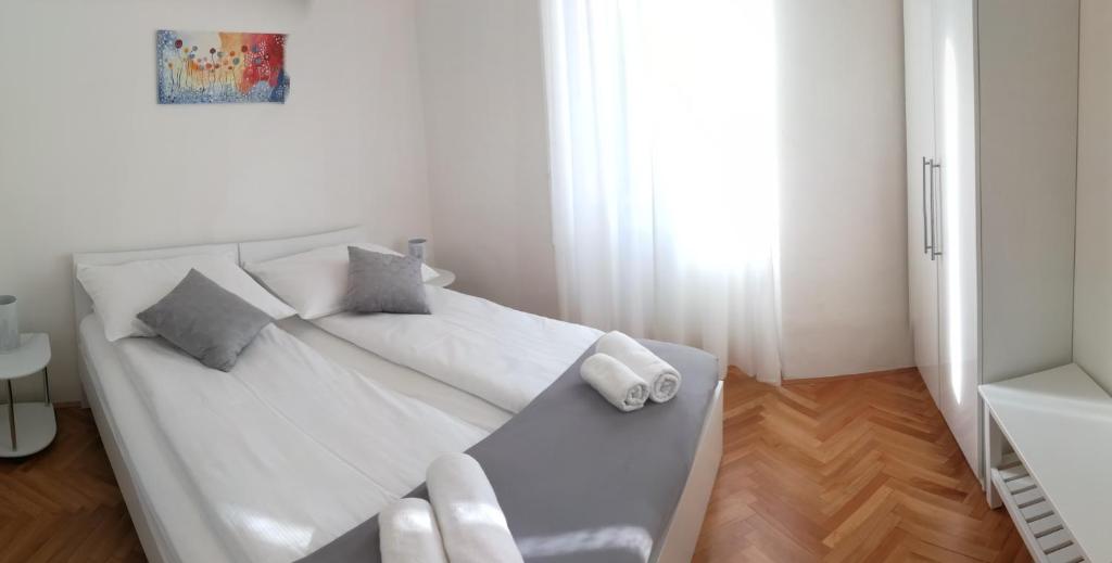 Dormitorio blanco con cama blanca y almohadas en Apartments B&M, en Sežana