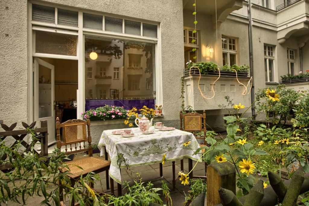 um pátio com uma mesa, cadeiras e flores em Pension Friedrich-Wilhelm em Berlim