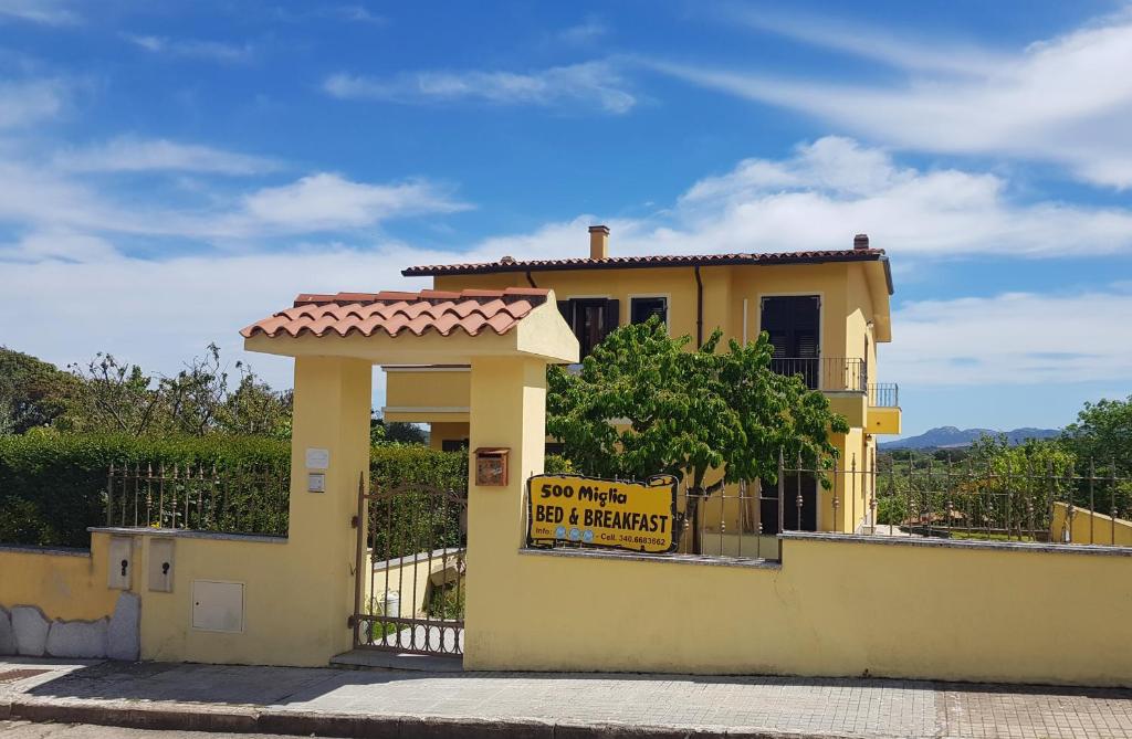 ein gelbes Haus mit einem Schild an der Seite in der Unterkunft B&B 500 Miglia  in Tempio Pausania