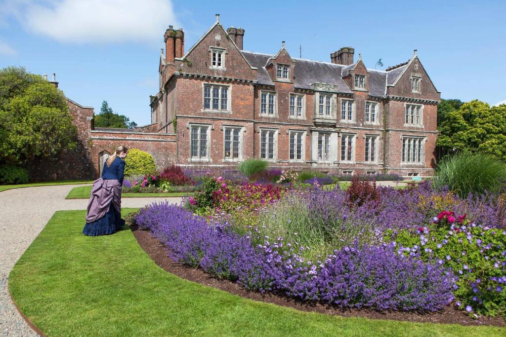une femme debout dans un jardin en face d'un château dans l'établissement Self Catering - The Garden House, à Wexford