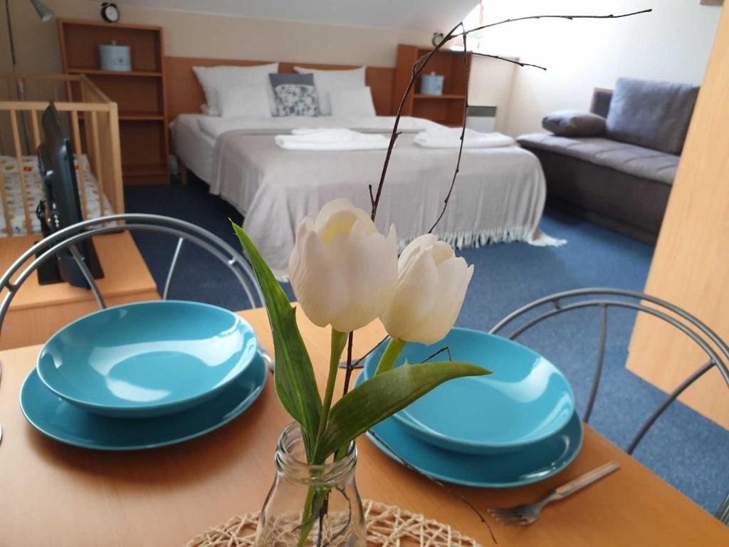 a table with two blue plates and a vase with flowers at Hotel Modrásek in Kašperské Hory