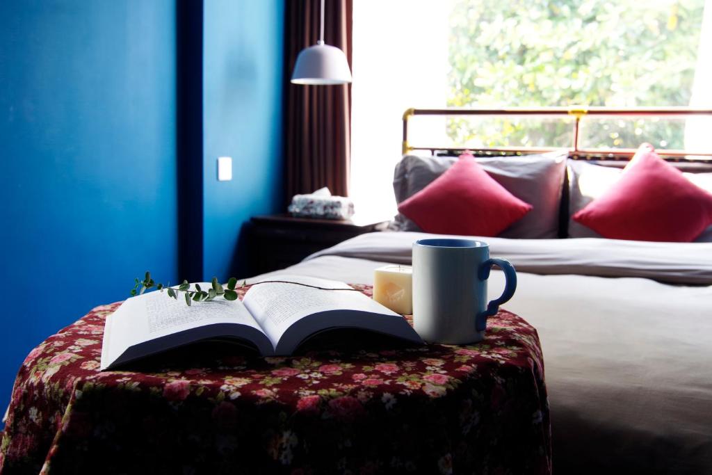 杭州市にあるHangzhou JiuYueJi Bed&Breakfastの- コーヒーとコーヒーマグカップを片手にスツールの本