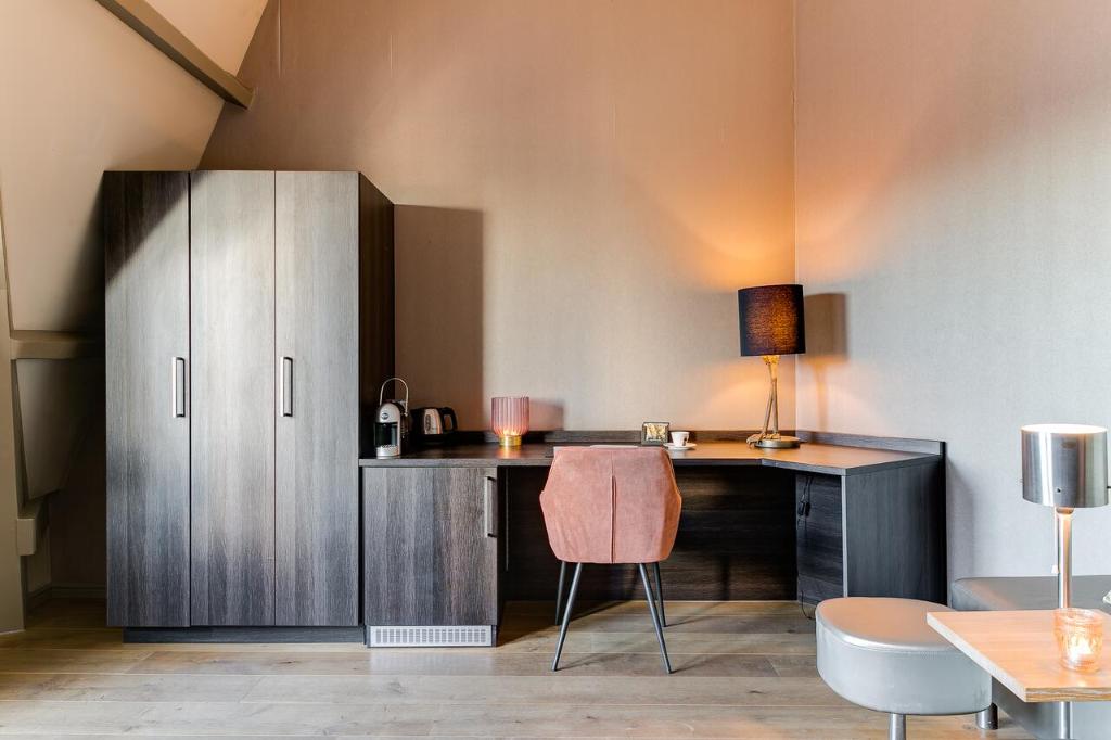 una scrivania con lampada e sedia in camera di Brasss Hotel Suites a Haarlem