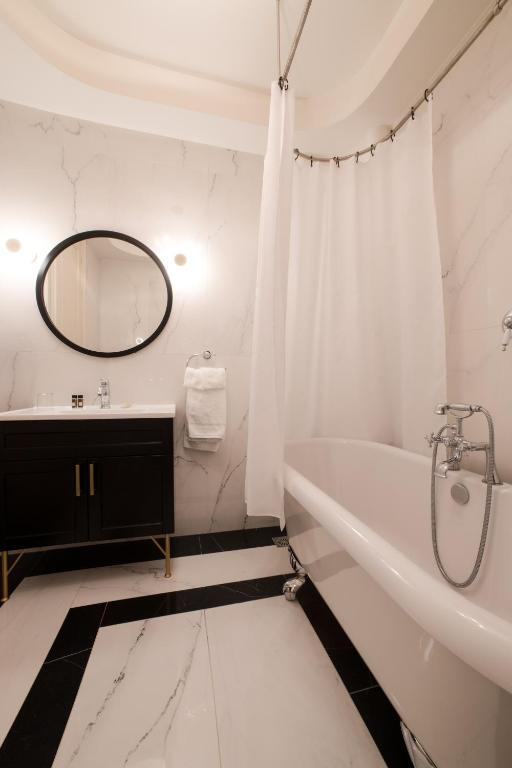 a white bathroom with a tub and a sink at Castellano Hotel & Suites in Nafplio