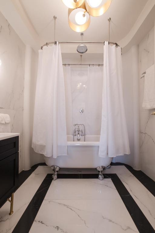 a white bathroom with a tub and a shower curtain at Castellano Hotel & Suites in Nafplio
