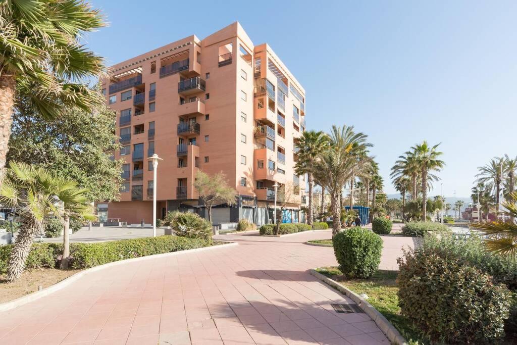 duży budynek apartamentowy z palmami i chodnikiem w obiekcie TGH Málaga we love the sea w Maladze