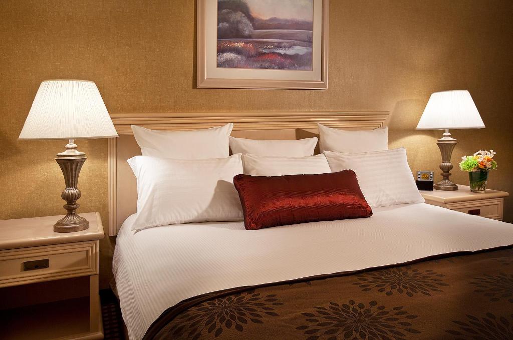 a large white bed with a red pillow on it at Coast Gateway Hotel in SeaTac