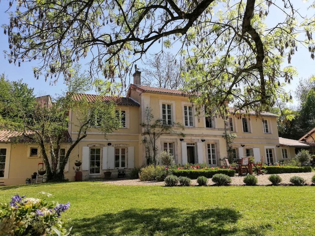 a large yellow house with a yard at Le Domaine Des Platanes in Bourg-Charente