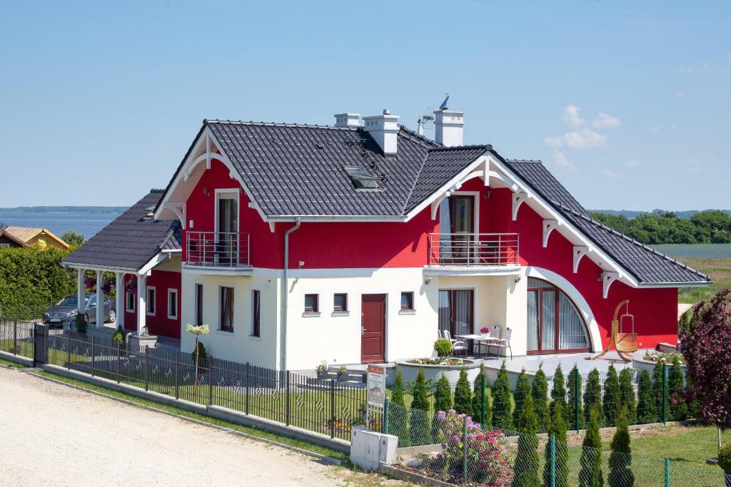 ein rotes und weißes Haus mit einem Zaun in der Unterkunft Villa Kamila in Międzywodzie