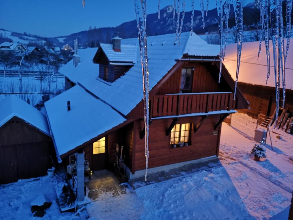 uma cabana de madeira na neve à noite em Drevenica Ľudmila pod Haťami em Terchová