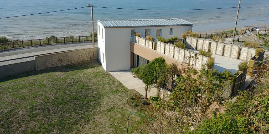 een wit huis naast de oceaan met een hek bij Brise du Large - Maison d'Ault in Ault
