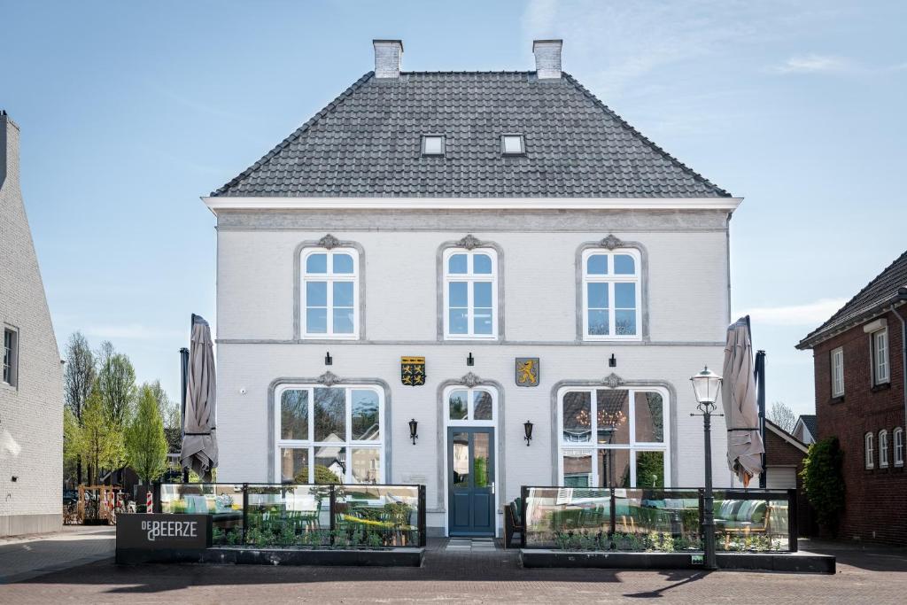 a white building with a black roof at Boutique Hotel De Beerze in Middelbeers