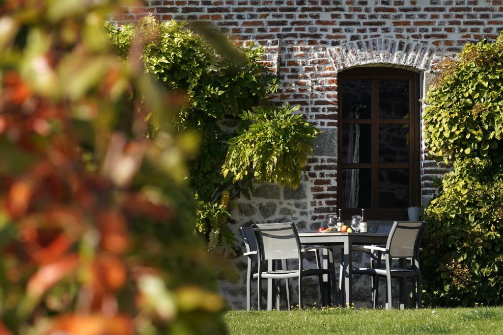 a table and chairs in front of a brick building at La Ferme du Parc - Gite Le Fournil in Montignies-lez-Lens