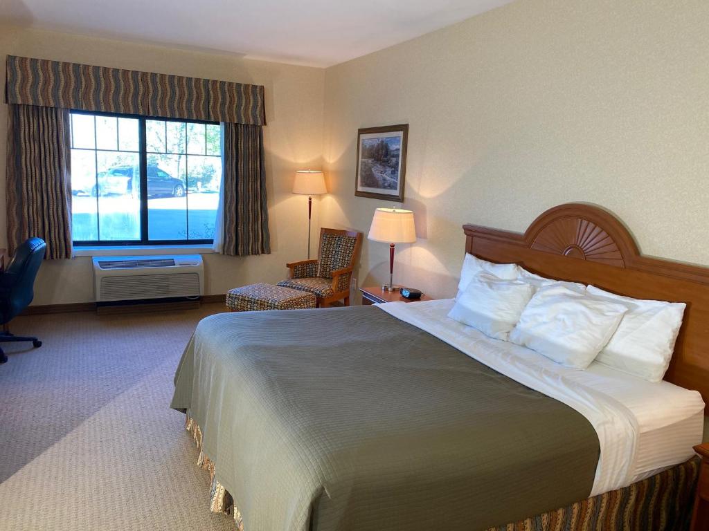 a hotel room with a large bed and a window at Red Coach Inn & Suites in Red Oak
