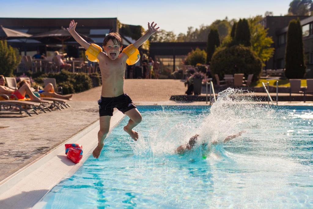 un jeune garçon sautant dans une piscine dans l'établissement Bø Hotel, à Bø