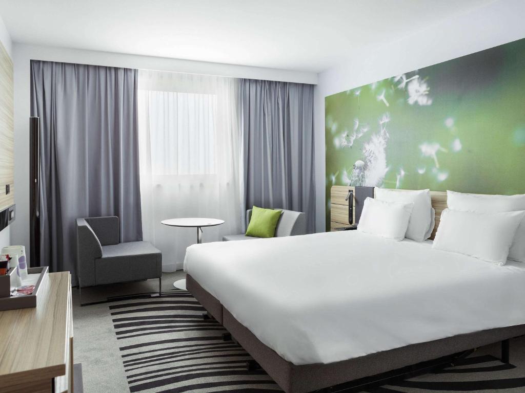 
a hotel room with a large bed and a large window at Novotel Paris Charles de Gaulle Airport in Roissy-en-France
