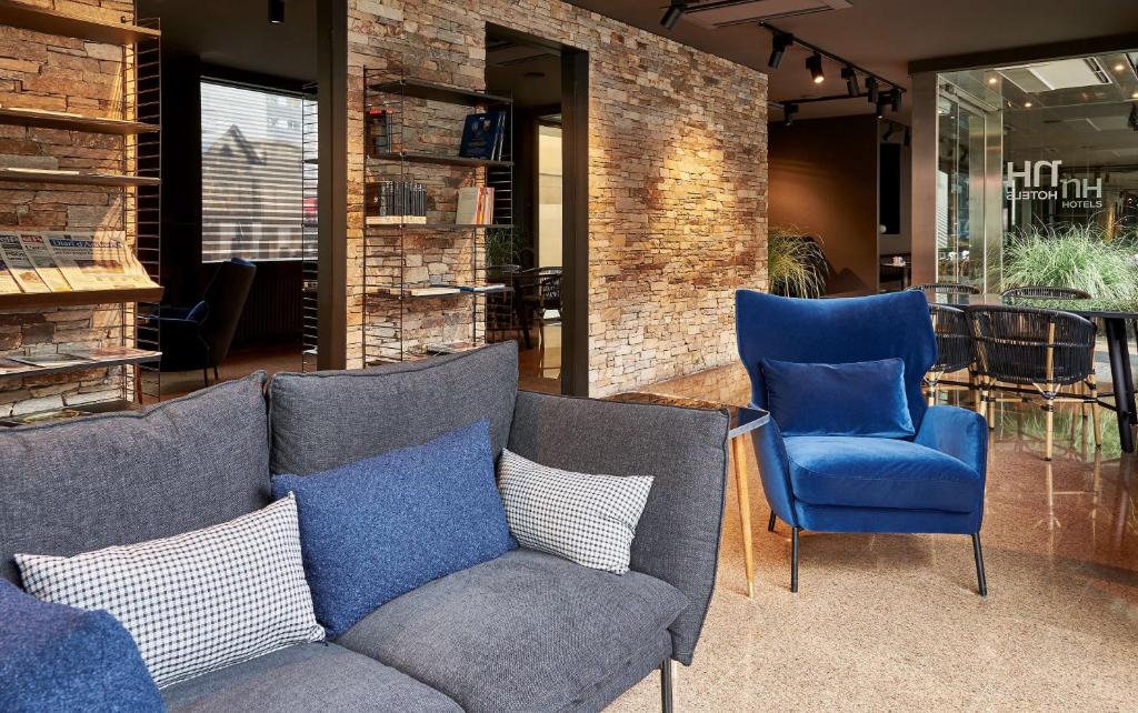 eine Couch und zwei blaue Stühle in einer Lobby in der Unterkunft NH Andorra la Vella in Andorra la Vella