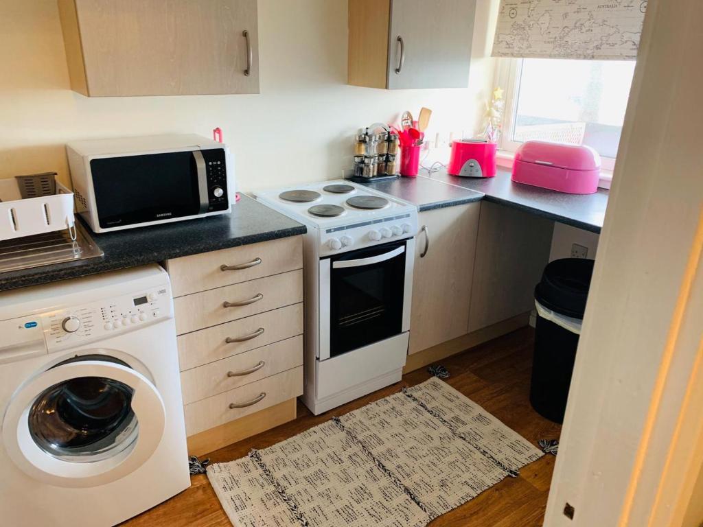 a kitchen with a washing machine and a microwave at CyCy Apartment in Aberdeen