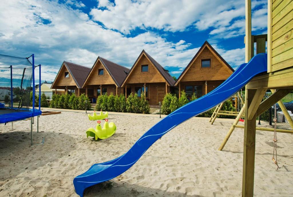 a playground with a blue slide in front of a house at Ross-domki in Sarbinowo