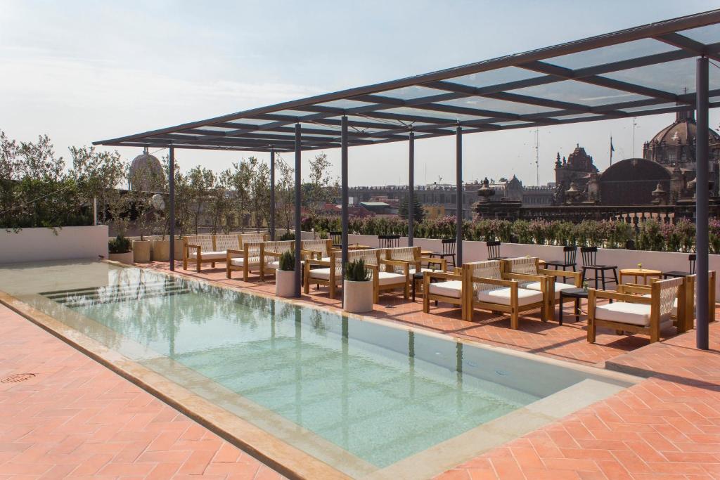einen Pool mit Stühlen und Tischen sowie einen Pavillon in der Unterkunft Círculo Mexicano, a Member of Design Hotels in Mexiko-Stadt