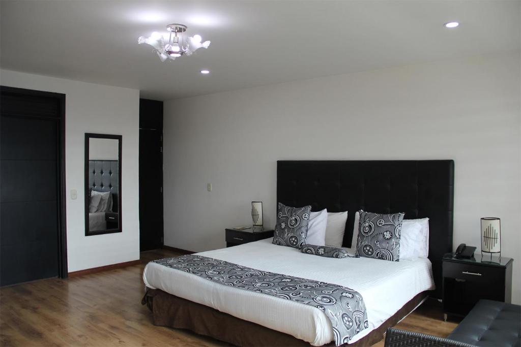 ボゴタにあるHotel Santafe Realのベッドルーム1室(大型ベッド1台、黒いヘッドボード付)