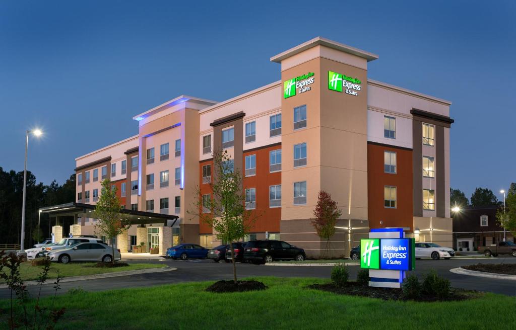 Holiday Inn Express & Suites - Fayetteville South, an IHG Hotel في فايتفيل: مبنى الفندق وامامه موقف سيارات