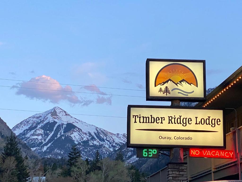 Timber Ridge Lodge Ouray في أوراي: وجود علامة على نزل جبلي خشبي مع جبل في الخلفية