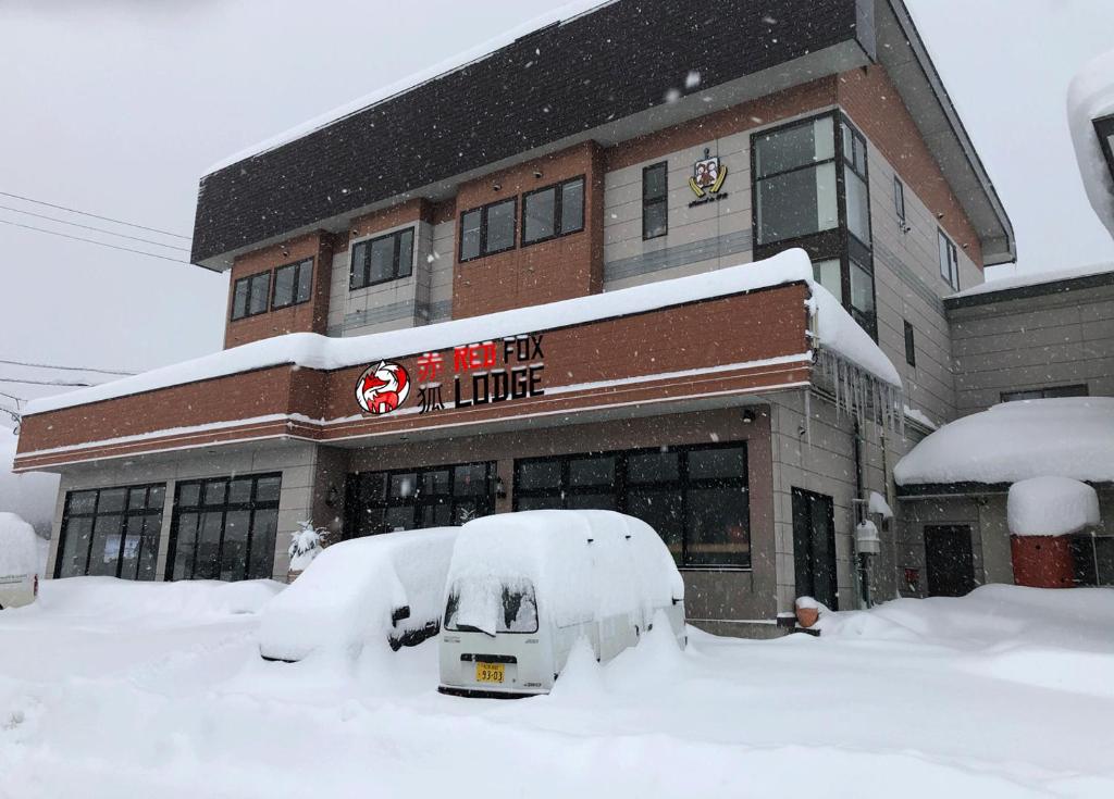 uma loja coberta de neve em frente a um edifício em Red Fox Lodge Myoko em Myoko