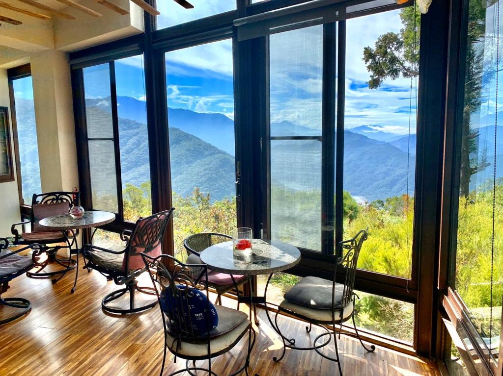 une chambre avec des tables, des chaises et de grandes fenêtres dans l'établissement Margaret Garden Villa, à Renai