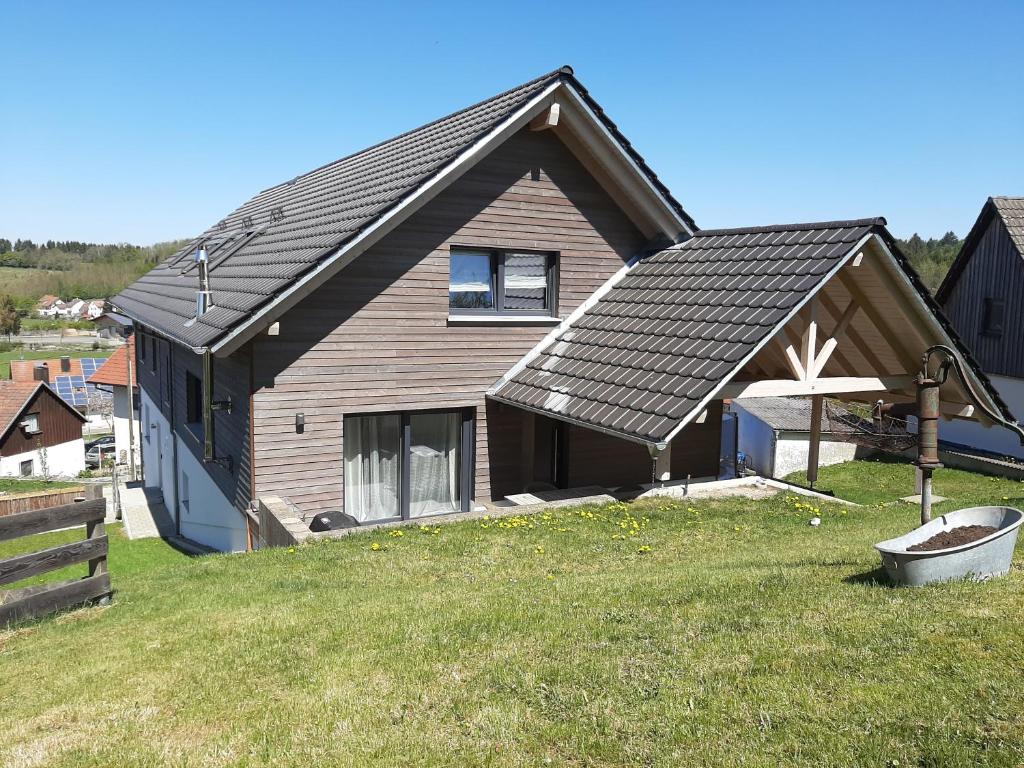 a house with a black roof on a grass field at Ferienwohnung Bergele in Rot an der Rot