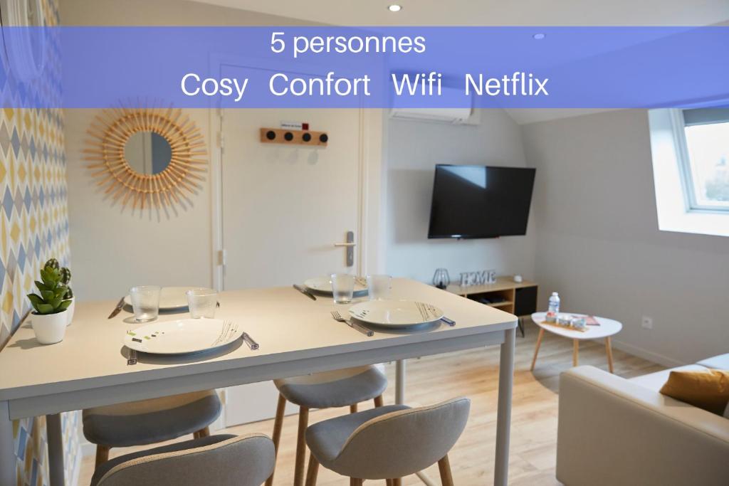 ein Esszimmer mit einem Tisch mit Stühlen und einem TV in der Unterkunft LocationsTourcoing - Le Famelart in Tourcoing