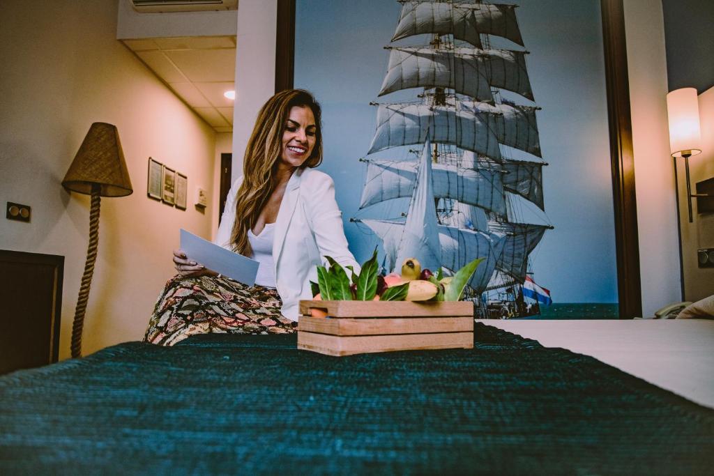 a woman sitting on a bed with a picture of a ship at Hotel Albaida Nature in Mazagón