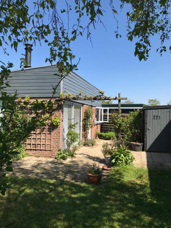 a brick house with a gate and a yard at Bungalow 221 in Noordwijkerhout