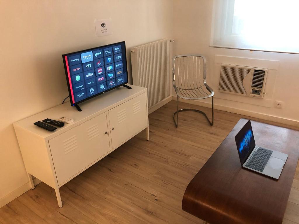 un salon avec une télévision et un ordinateur portable sur une table dans l'établissement LE CLIO CARRÉ D'OR BEACH APARTMENT, à Nice