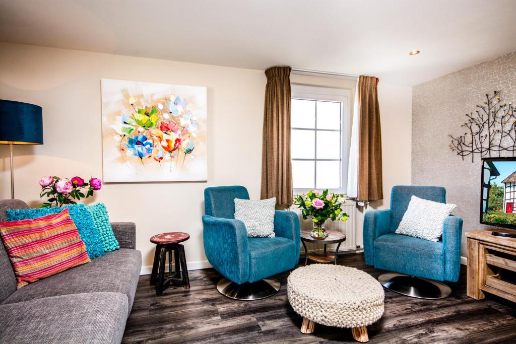 a living room with two blue chairs and a tv at Aparthotel Ons Epen in Epen