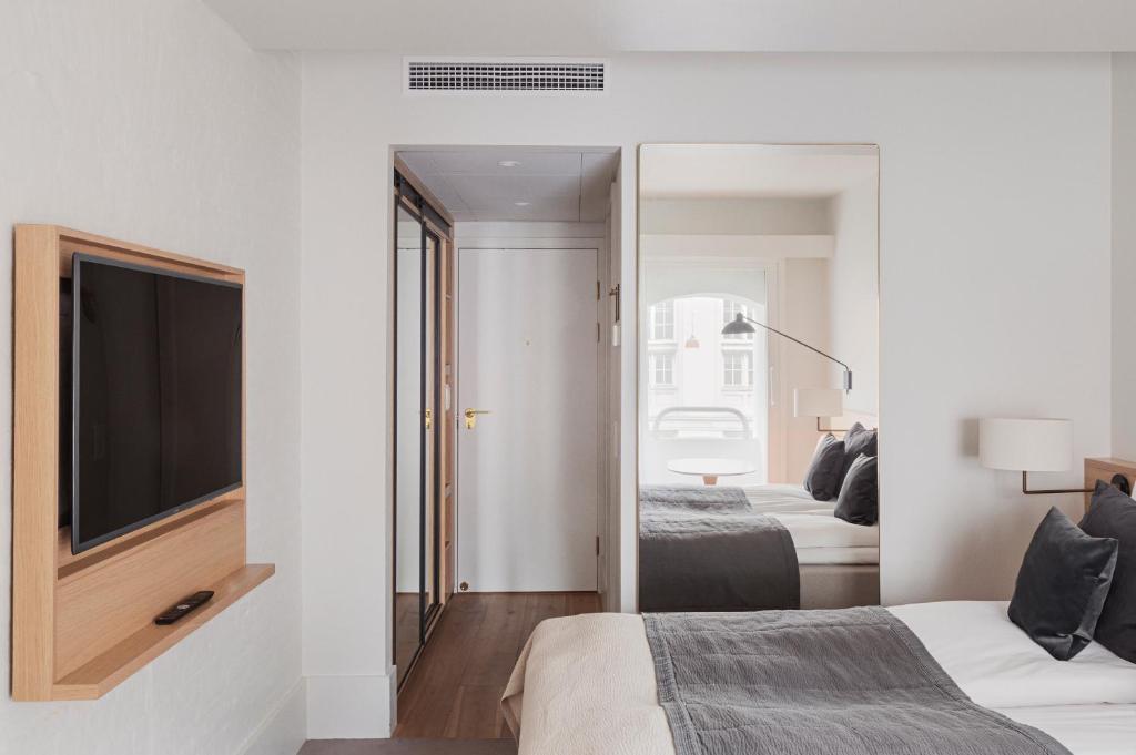 a bedroom with two beds and a tv and a mirror at Copenhagen Admiral Hotel in Copenhagen