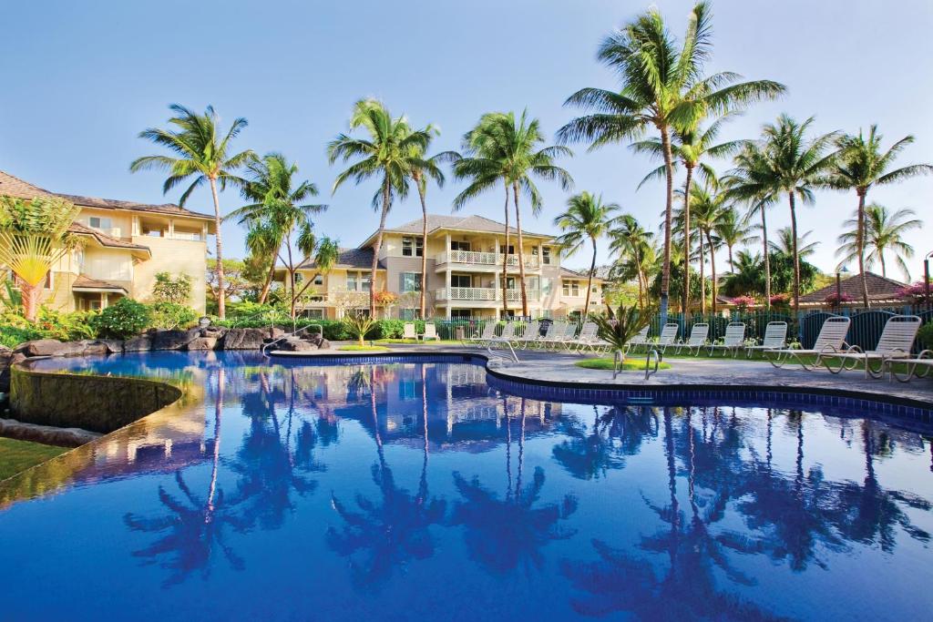 una piscina con palmeras y casas en Fairway Villas Waikoloa by OUTRIGGER, en Waikoloa