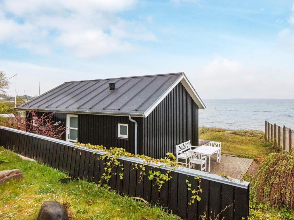 uma casa preta com um telhado preto ao lado do oceano em One-Bedroom Holiday home in Bjert 1 em Sønder Bjert