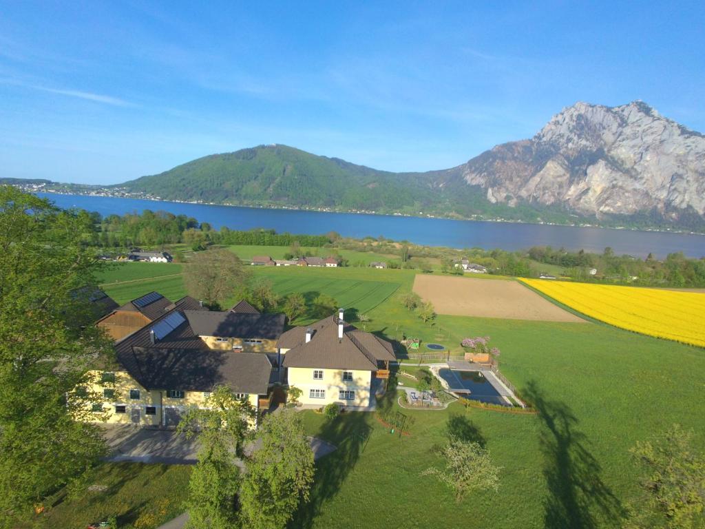 an aerial view of a house with a field and a lake at Landgut Wagnerfeld in Altmünster